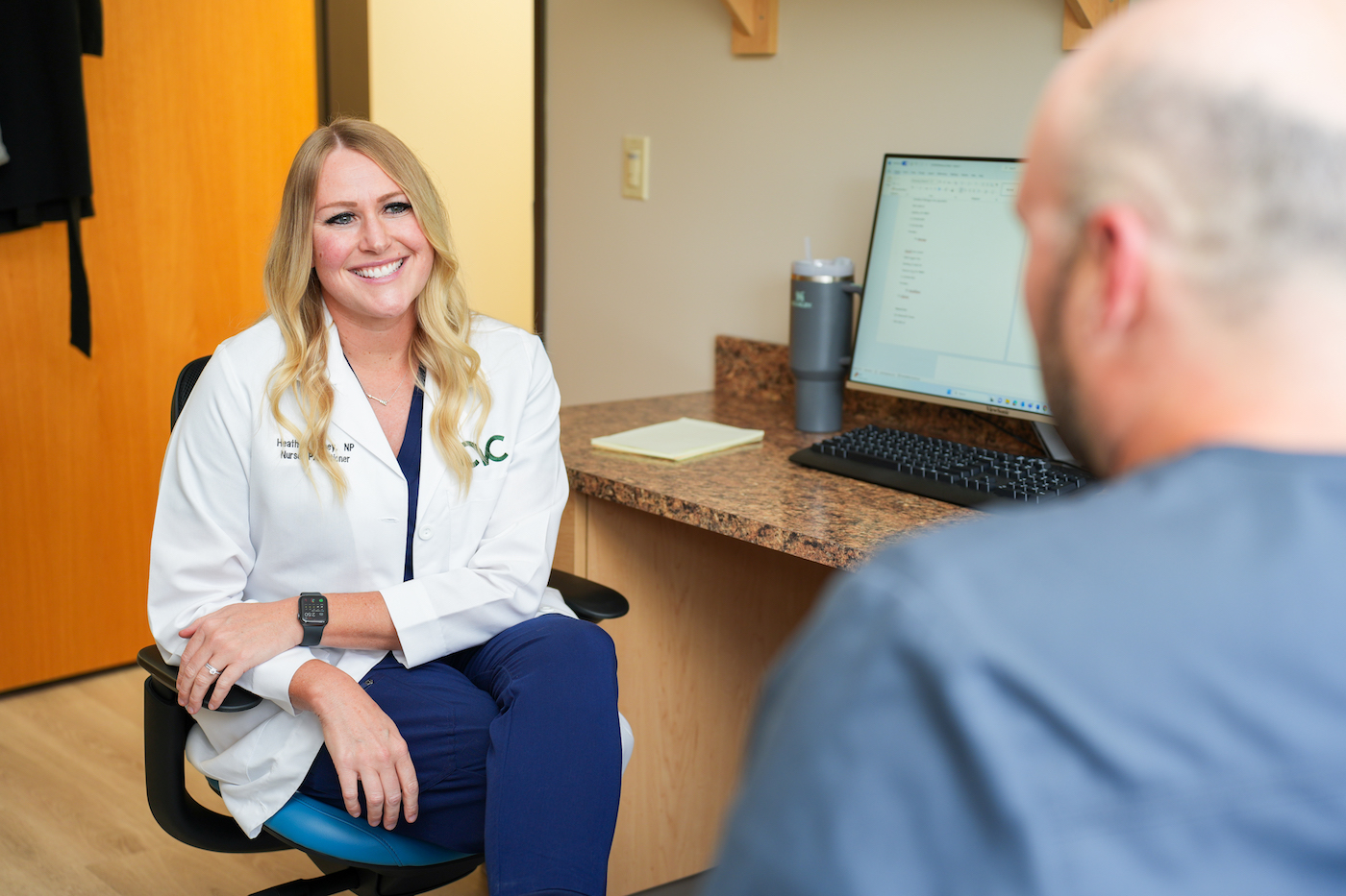 Nurse Practitioner Heather Richey has conversation with office manager in bright, sunny office.